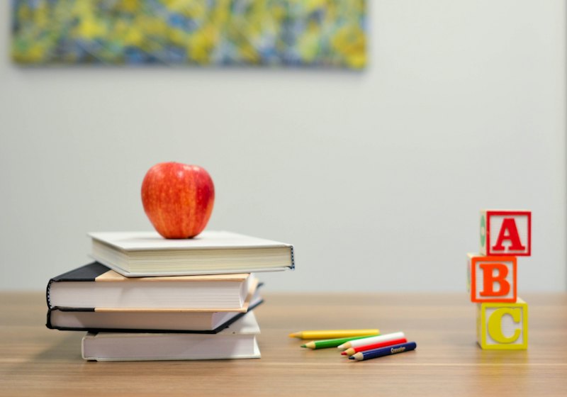 Books, an apple, crayons and ABC blocks on a desk